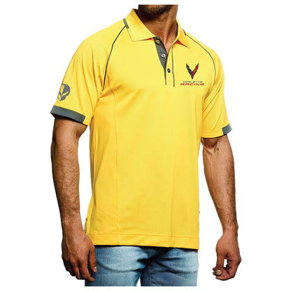 Alt view of Corvette Racing "JAKE" Polo - Yellow/Gray - A man wearing a bright yellow short-sleeve polo shirt with gray trim on the collar, sleeve cuffs, and shoulders, featuring a 'VRAI MACHINES' logo on the left chest and a matching sleeve graphic. He is wearing blue jeans against a plain white background.